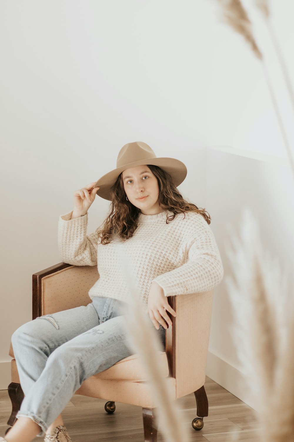 woman in white long sleeve shirt and blue denim jeans sitting on brown wooden chair