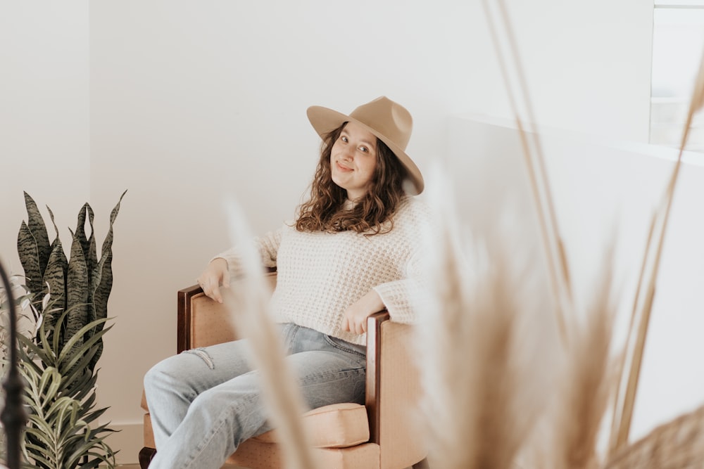 woman in white knit sweater and blue denim jeans sitting on brown wooden chair