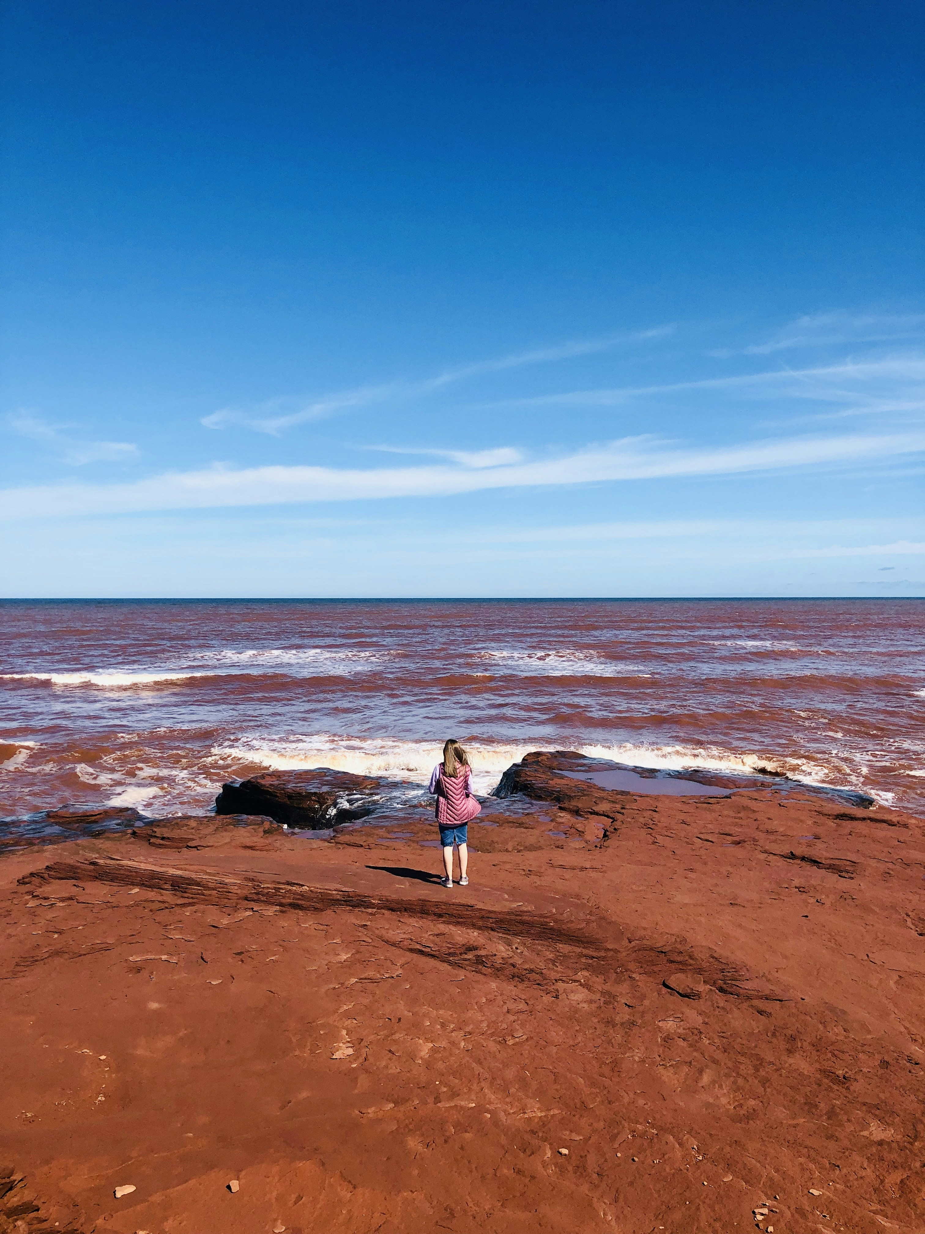 woman in white dress standing on brown sand near body of water during daytime