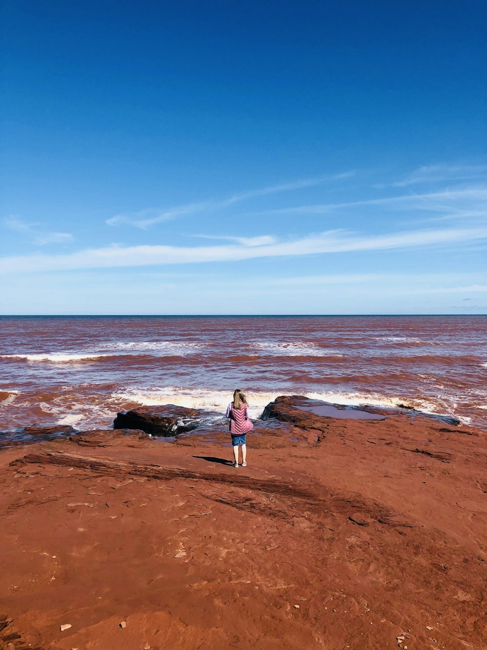 woman in white dress standing on brown sand near body of water during daytime