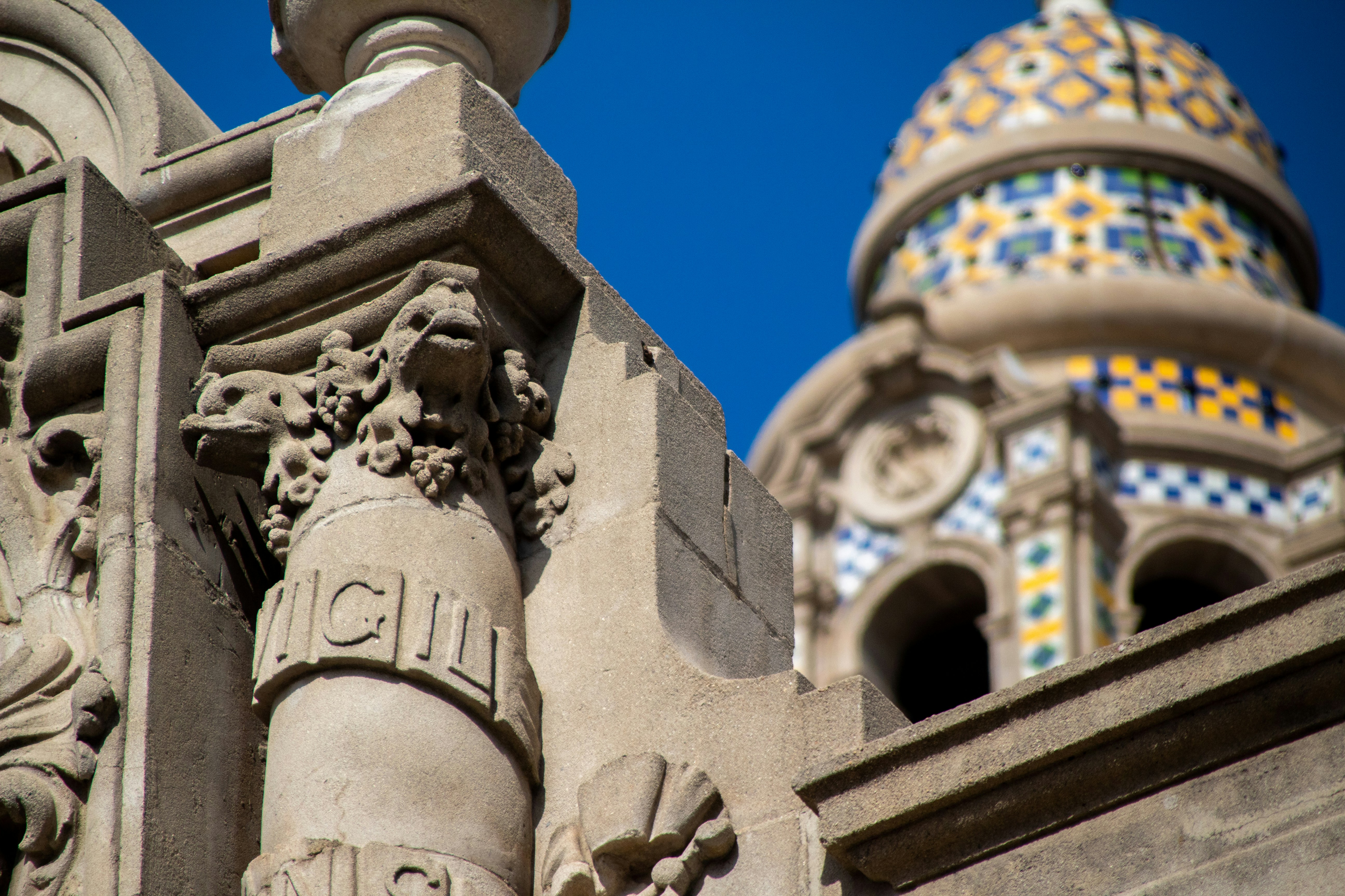low angle photography of concrete statue under blue sky during daytime, Ramparts in foreground, California Tower in background. 
