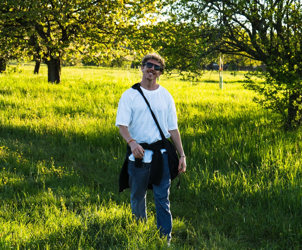 man in white crew neck t-shirt standing on green grass field during daytime