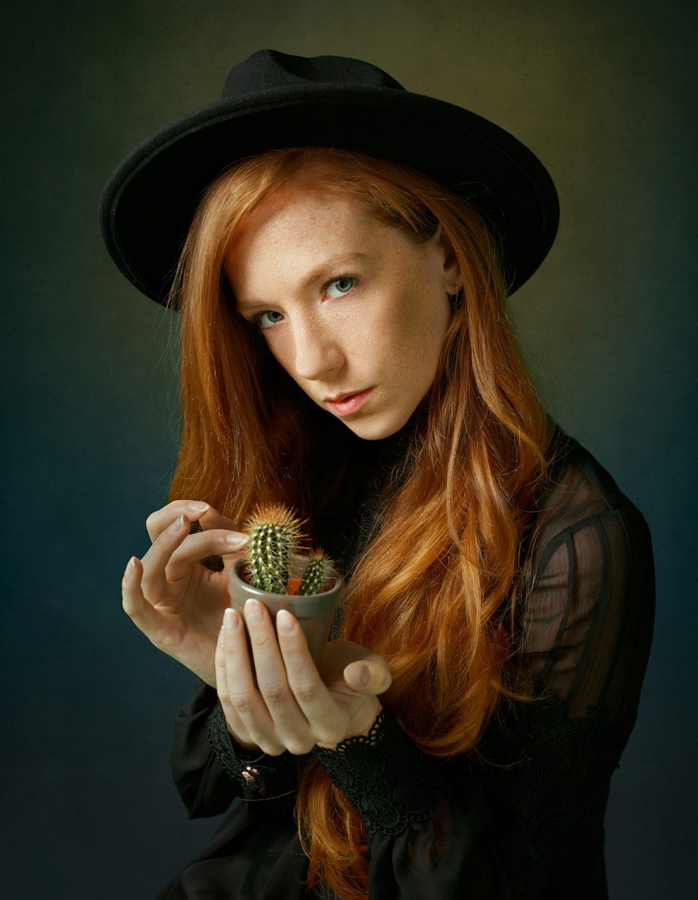 woman in black hat holding white and green cactus