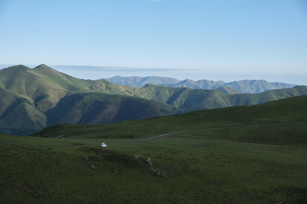 green grass field and mountains under blue sky during daytime