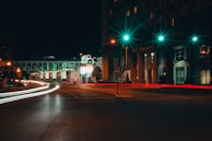 A nighttime street scene illuminated by neon lights and traffic.