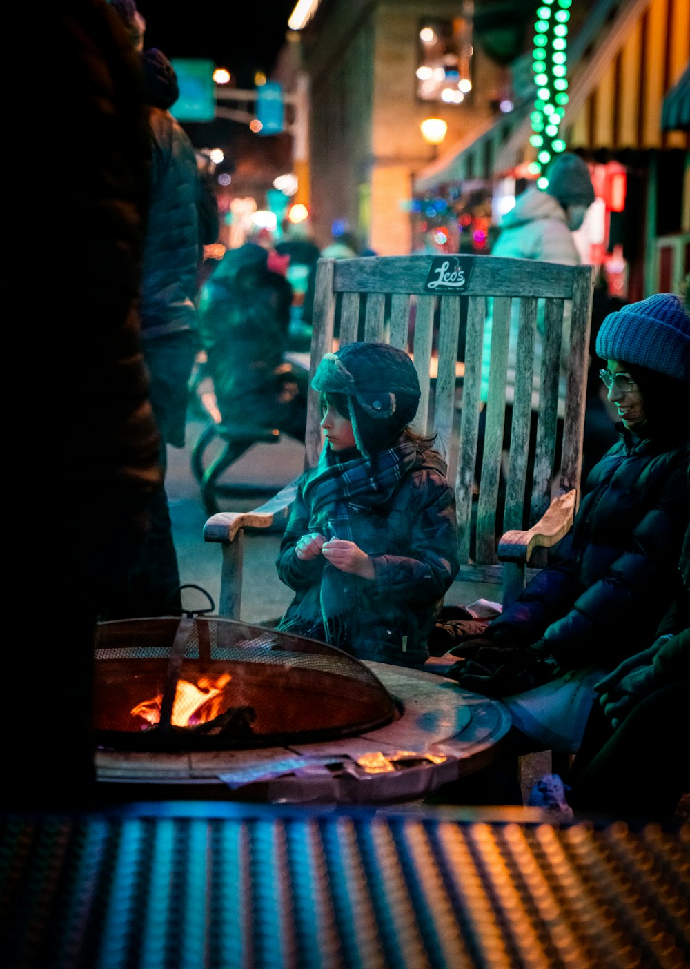 2 boys sitting on chair in front of fire pit