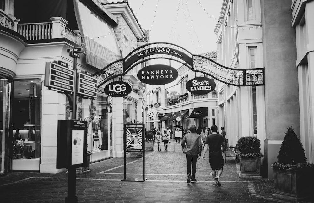 grayscale photo of people walking on street near building