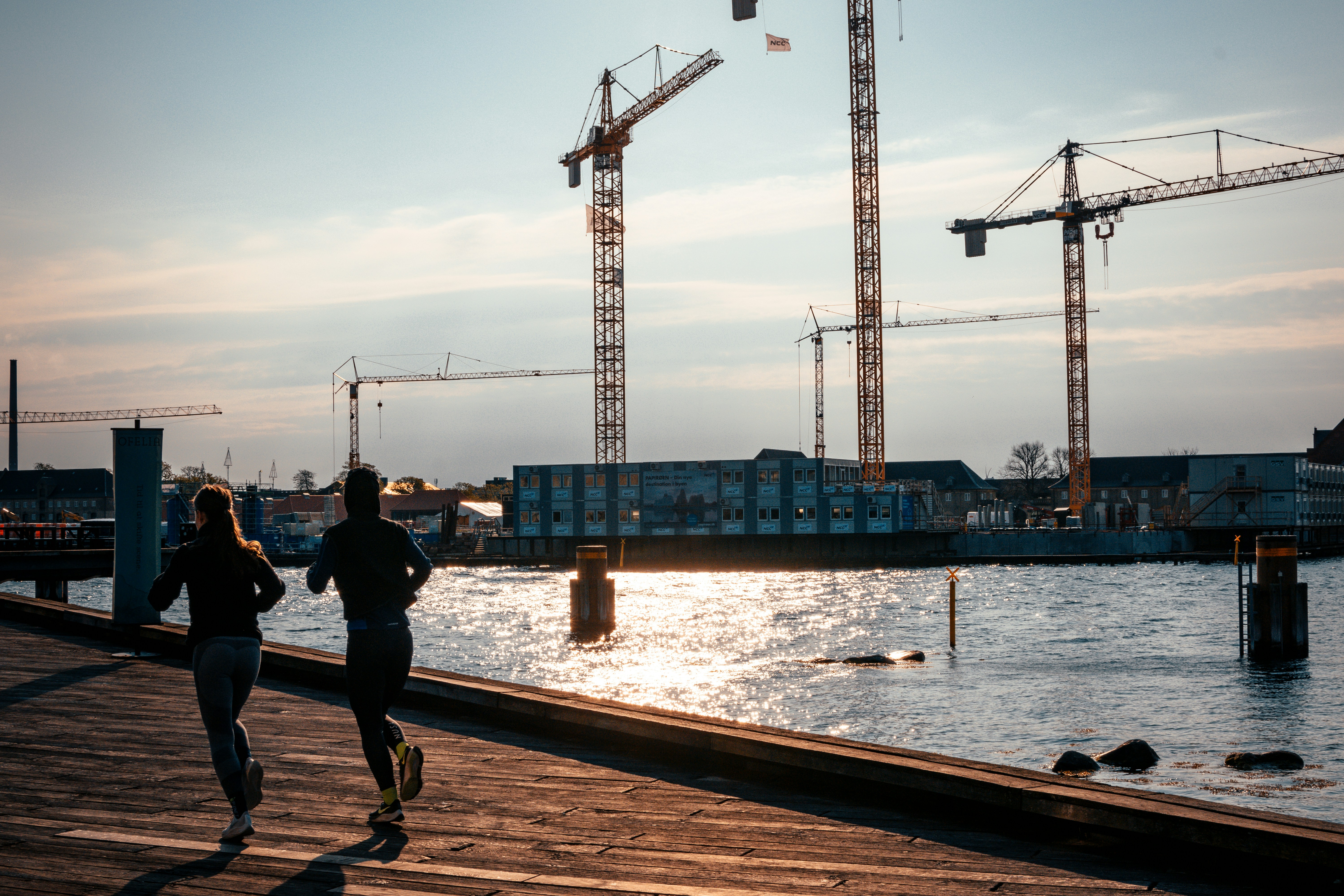 uomo in giacca nera e pantaloni neri in piedi vicino allo specchio d'acqua durante il giorno