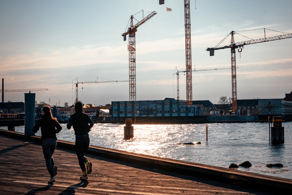 man in black jacket and black pants standing near body of water during daytime