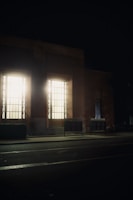 A slim, illuminated lightbox mounted on a modern retail storefront at dusk.