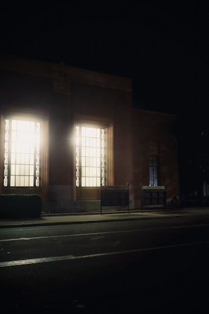 A slim, illuminated lightbox mounted on a modern retail storefront at dusk.