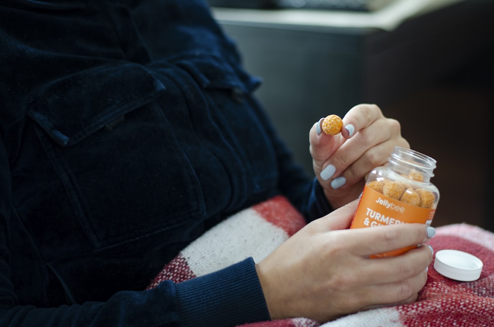 person holding orange plastic bottle