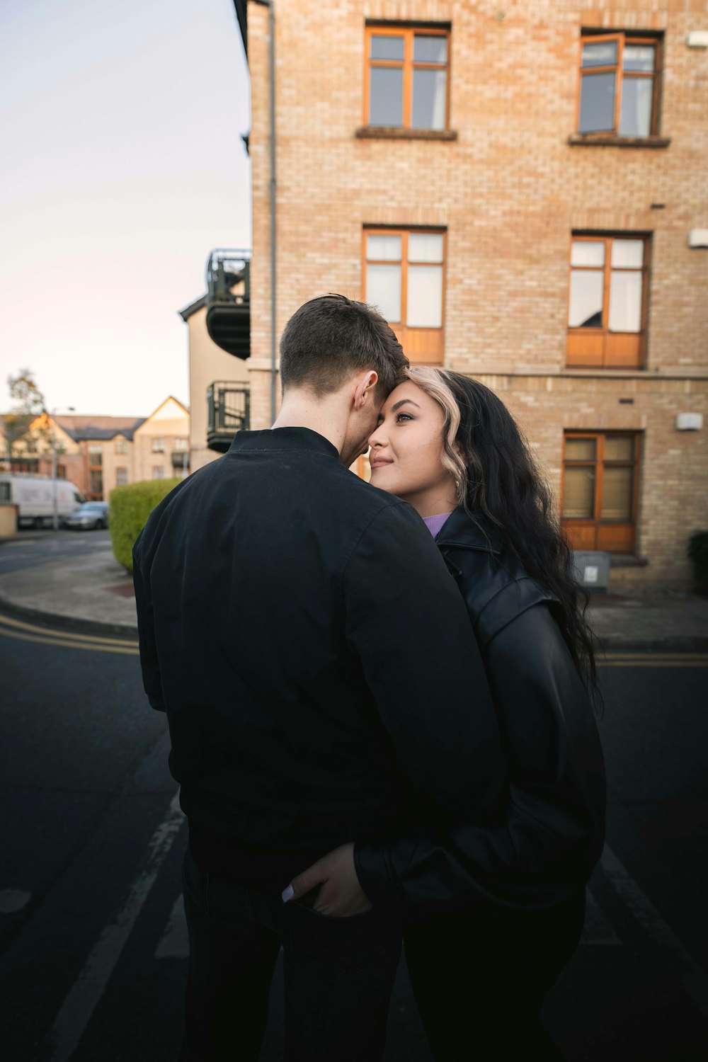 man in black jacket hugging woman in black jacket