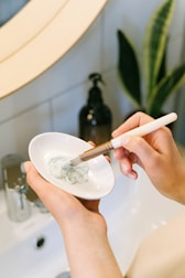 person holding white ceramic bowl with silver spoon