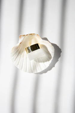 Elegant glass jar filled with authentic Ibiza sand, resting on a smooth beige fabric with soft sunlight.