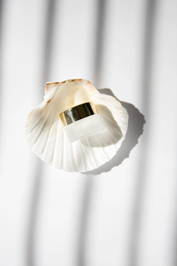 Elegant glass jar filled with authentic Ibiza sand, resting on a smooth beige fabric with soft sunlight.