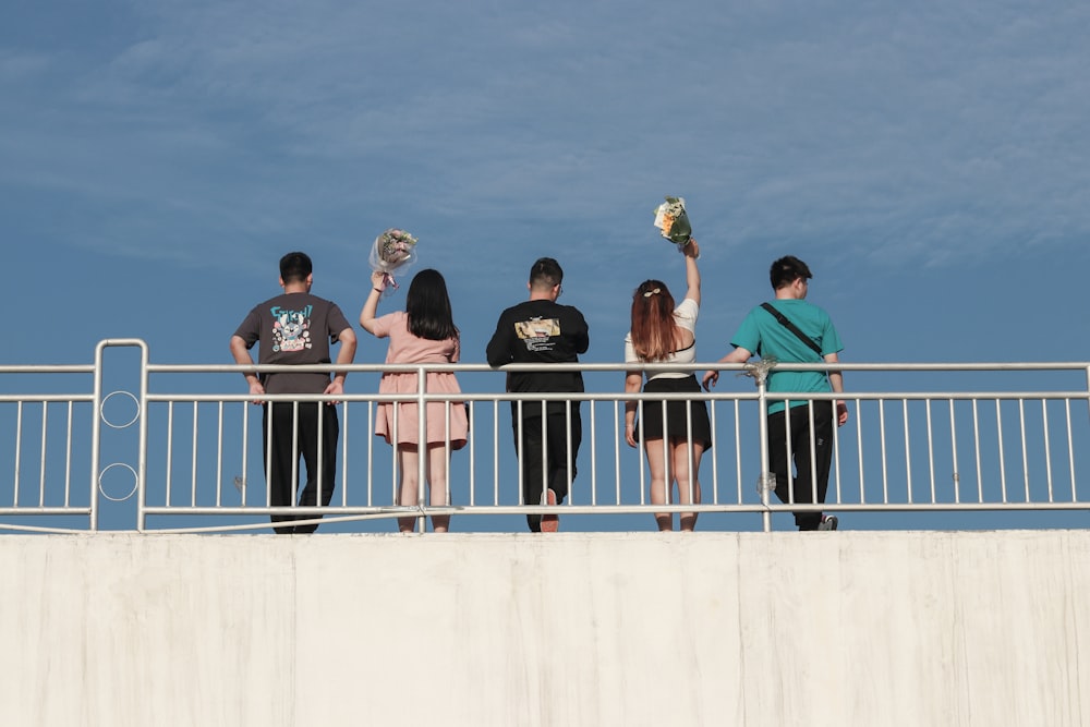 group of people standing on white concrete wall during daytime