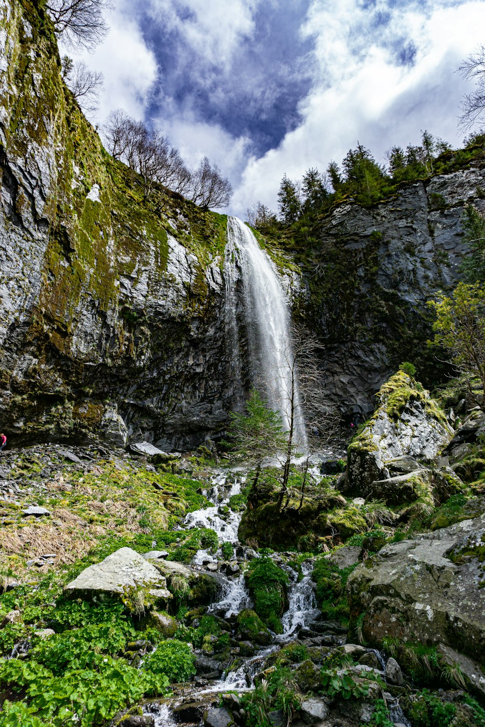 Cascate sulla montagna rocciosa sotto il cielo nuvoloso durante il giorno