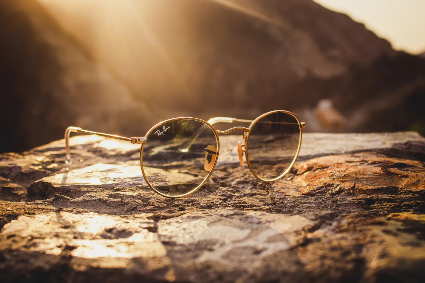 Gold aviator sunglasses resting on warm brown stone
