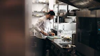 A chef in a restaurant kitchen using hygiene products to maintain cleanliness.