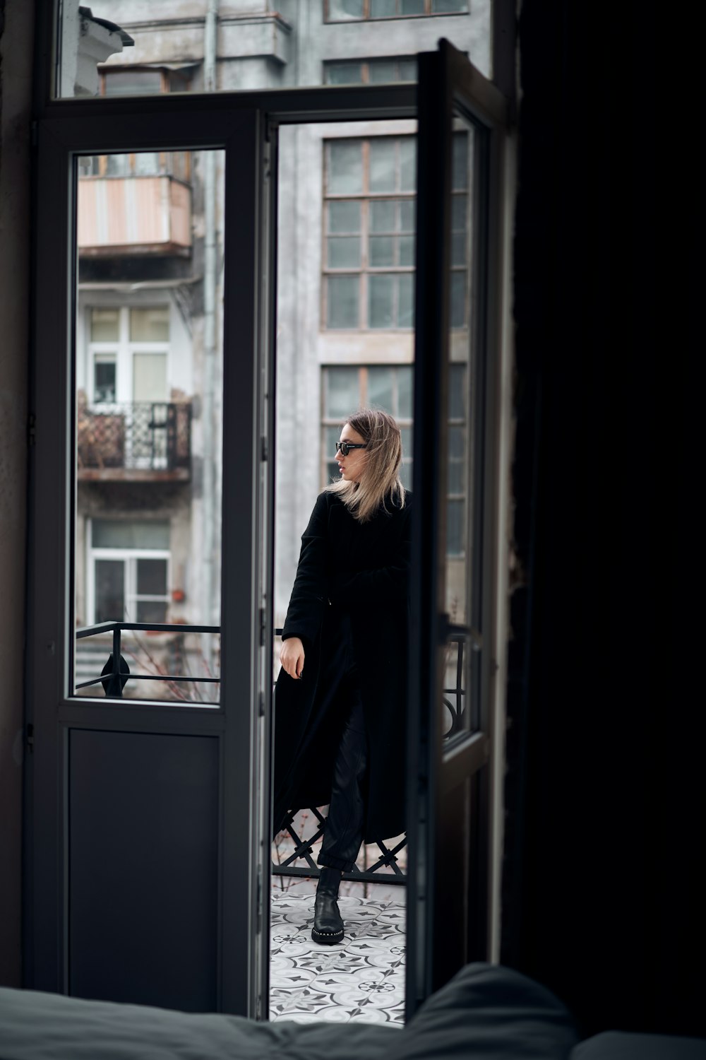 ガラス窓の前に立つ黒いコートの女性