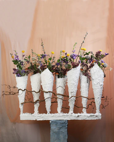 A set of stoneware vases in cheerful reds and blues, arranged with fresh wildflowers.