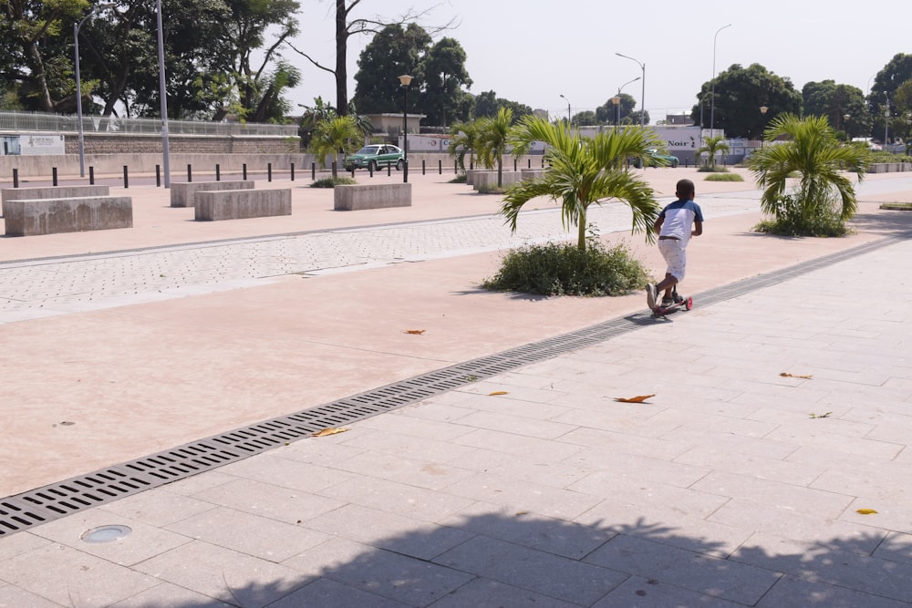 man in white t-shirt and black pants walking on sidewalk during daytime