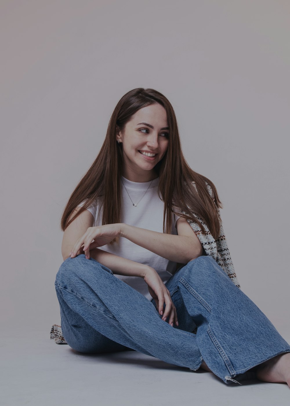 woman in white shirt and blue denim jeans sitting on floor