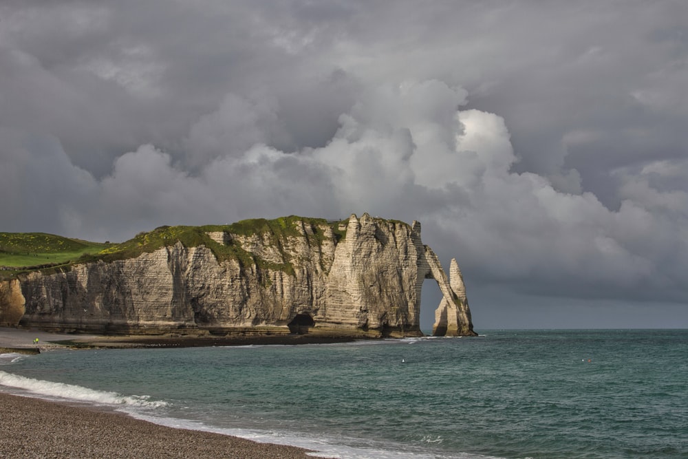 brown rock formation on sea under white clouds during daytime