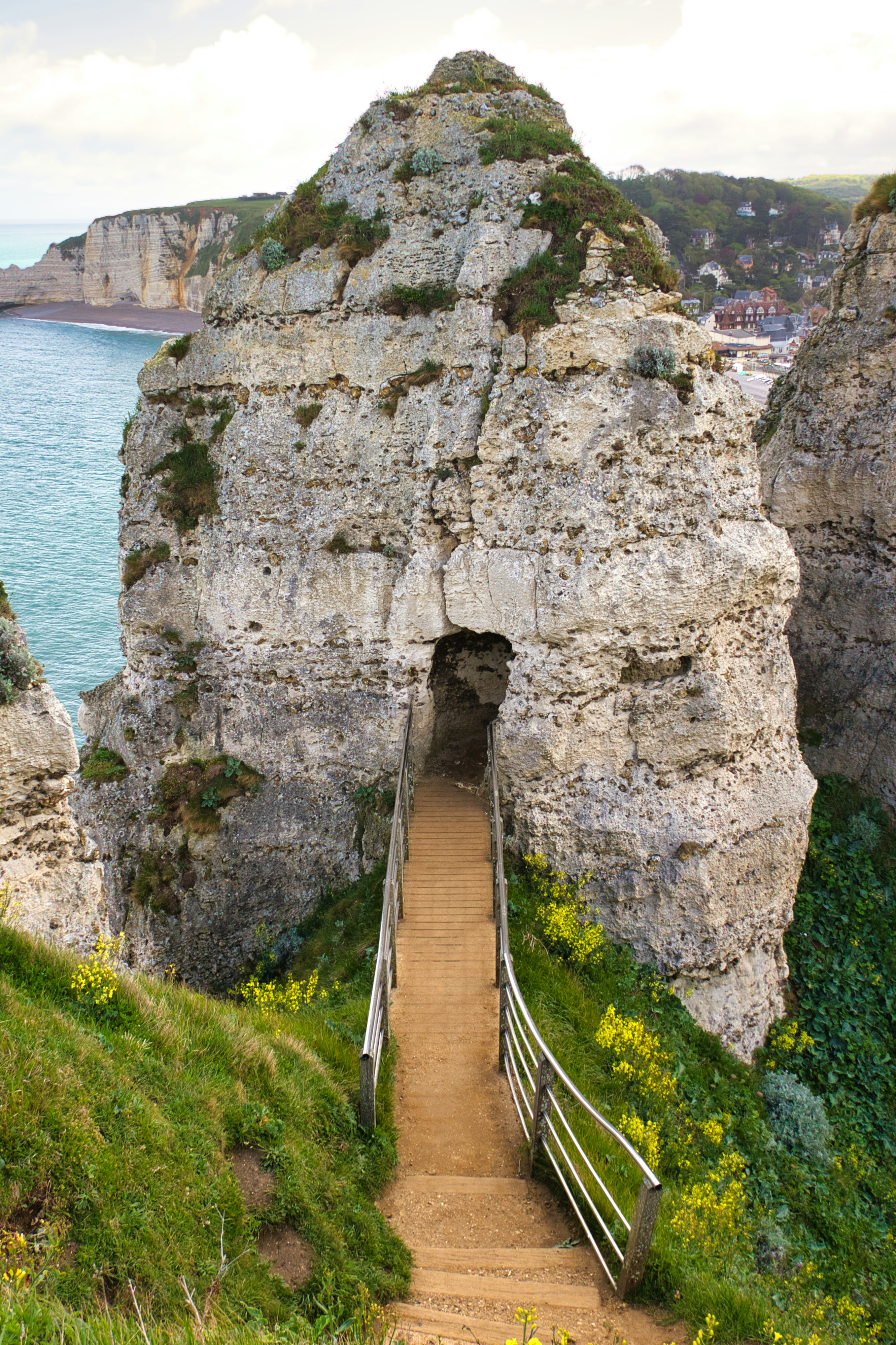 낮 동안 수역 근처의 회색 암석에 갈색 나무 다리