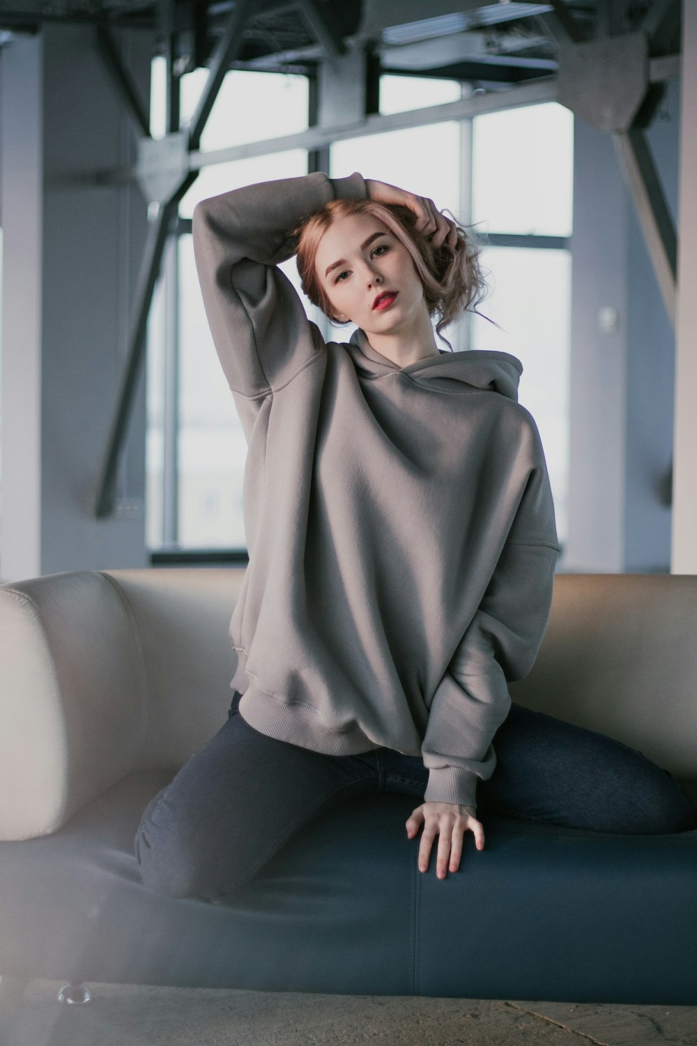 woman in gray hoodie and black pants sitting on gray couch