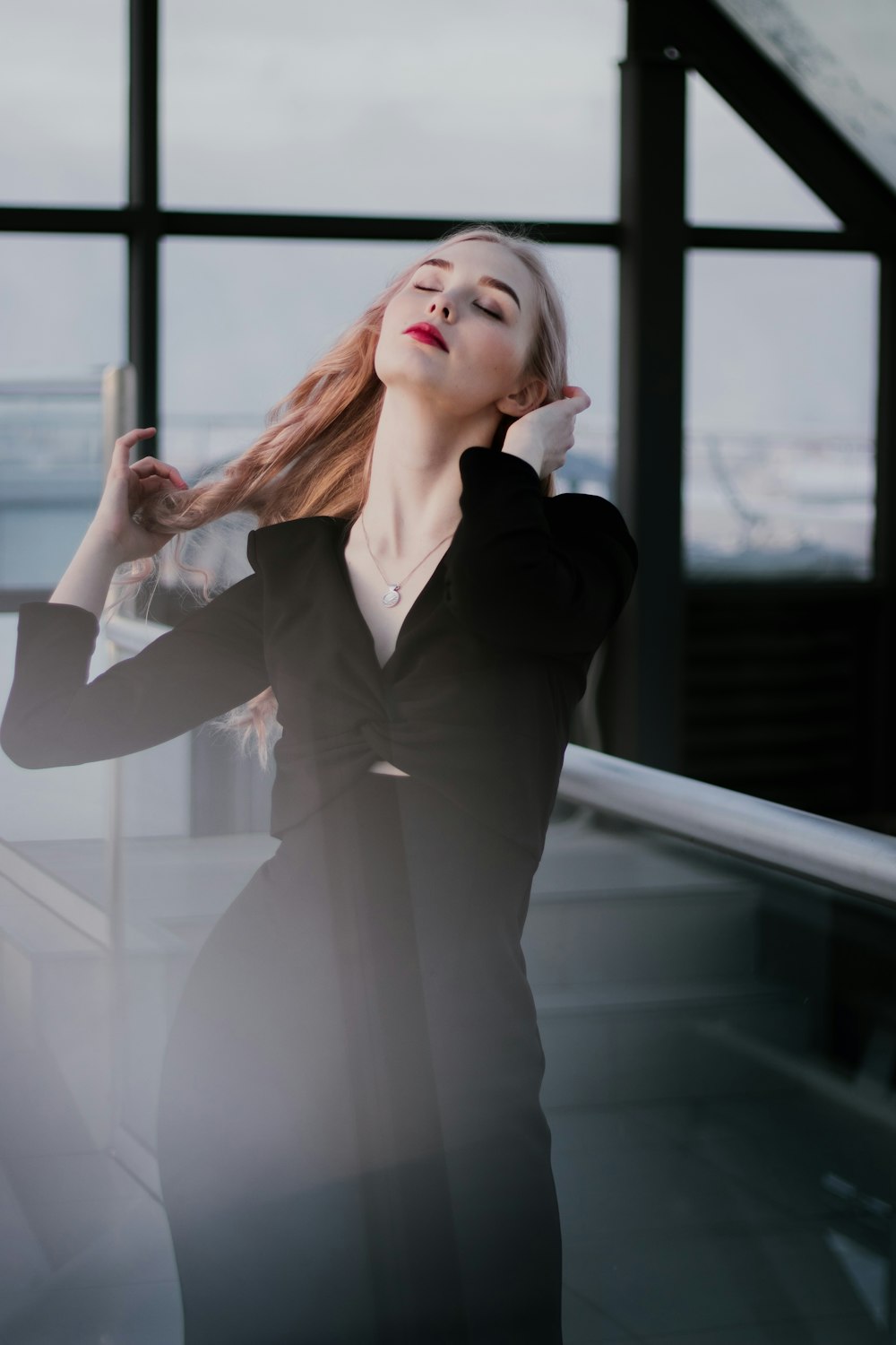 a woman with red hair is standing near a window