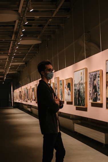 man in black suit standing near paintings