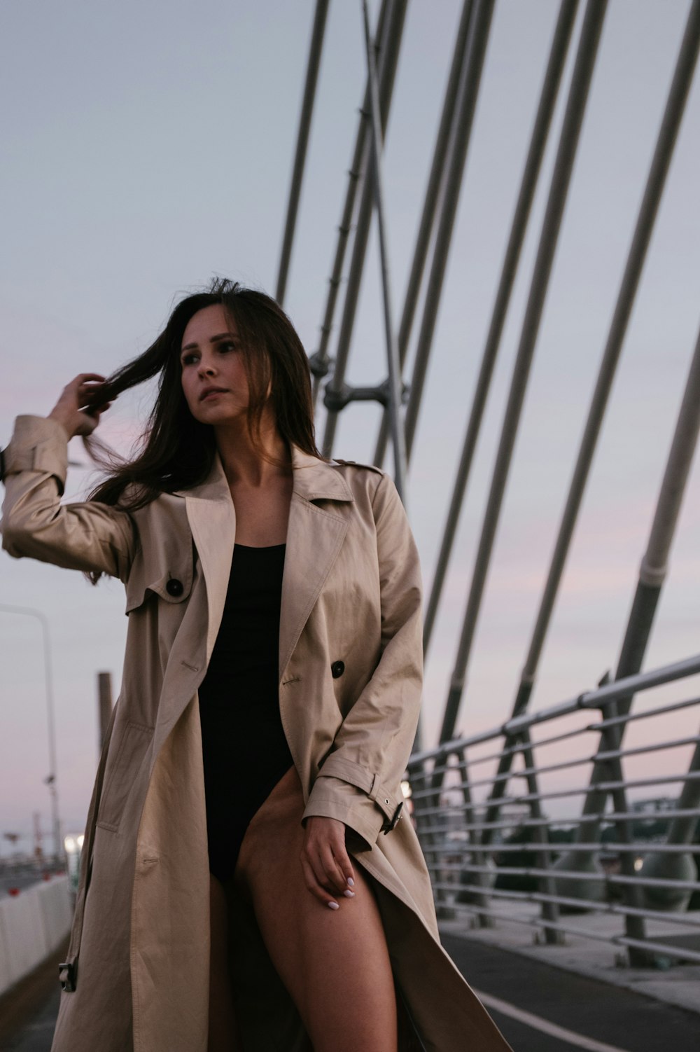 woman in brown coat standing on bridge during daytime