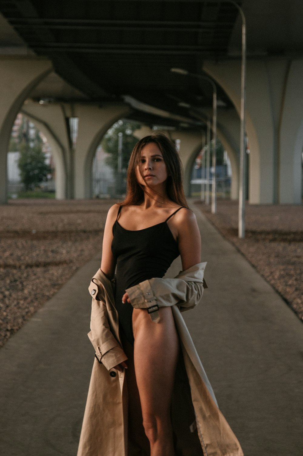 woman in black spaghetti strap top and brown coat standing on train rail during daytime