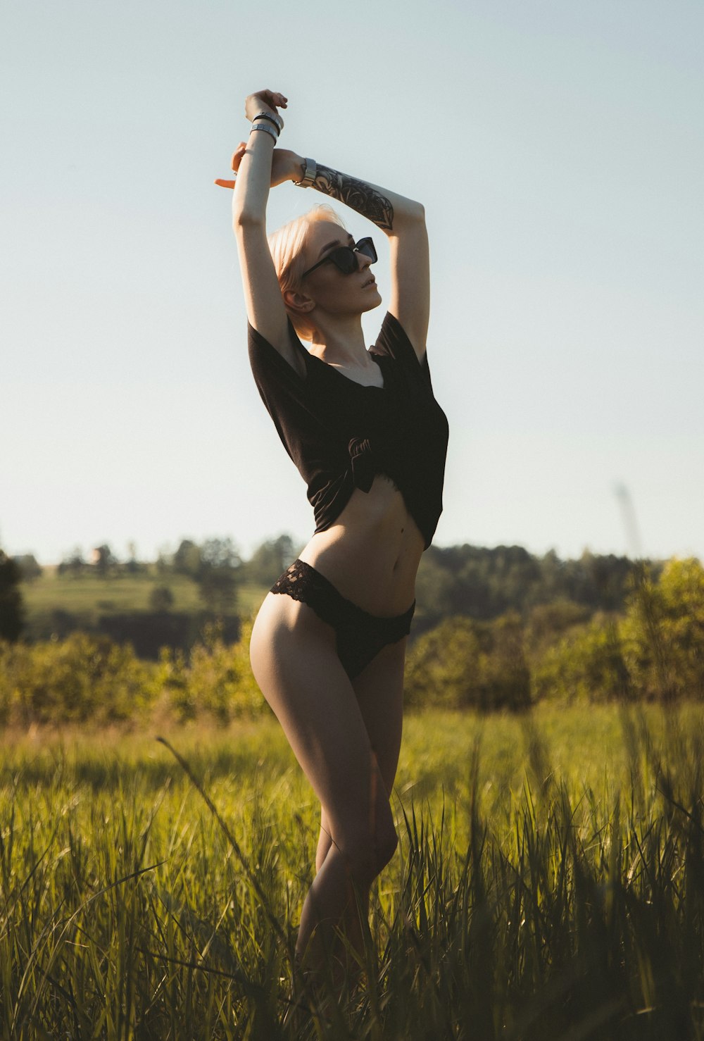 woman in black crop top and black panty standing on green grass field during daytime
