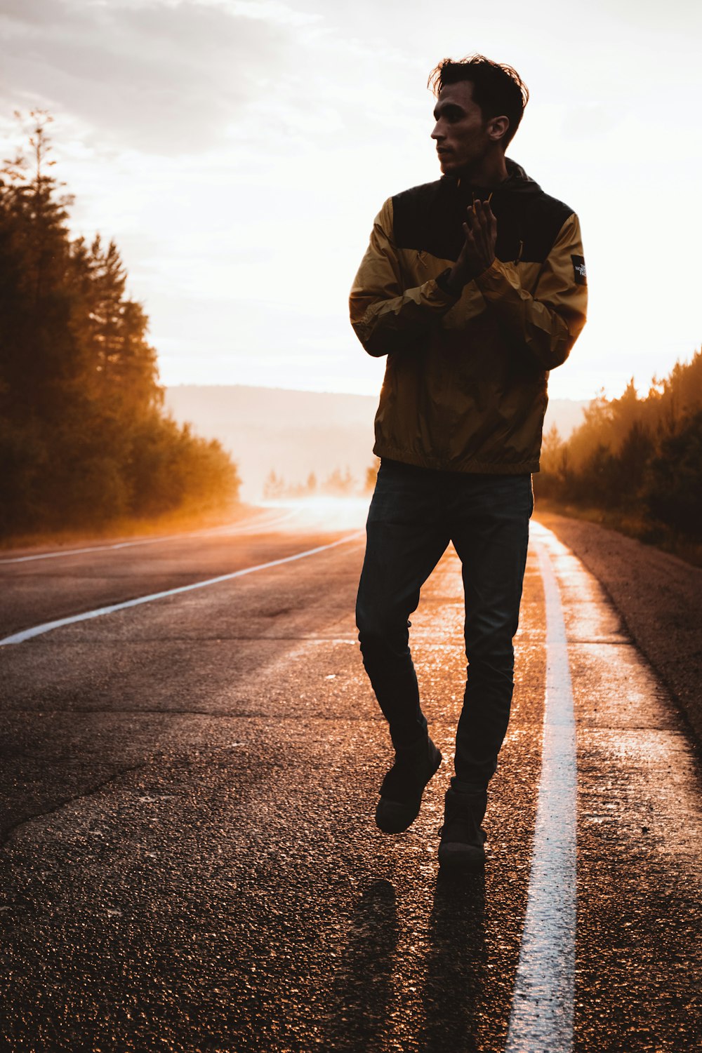 man in brown jacket and black pants standing on road during daytime