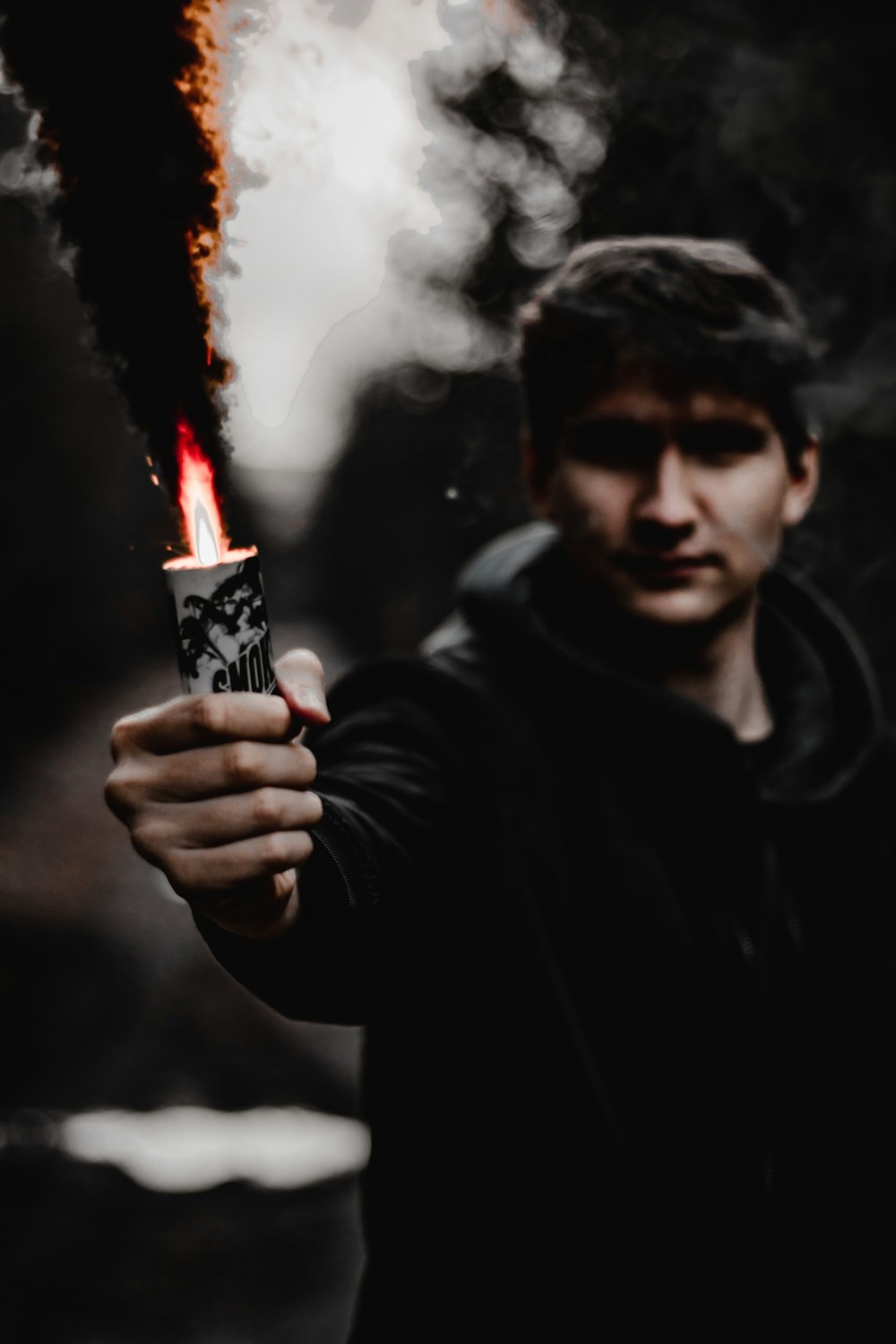 Mann in schwarzem Kapuzenpullover mit Feuerzeug