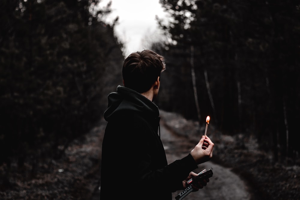 man in black hoodie holding black smartphone