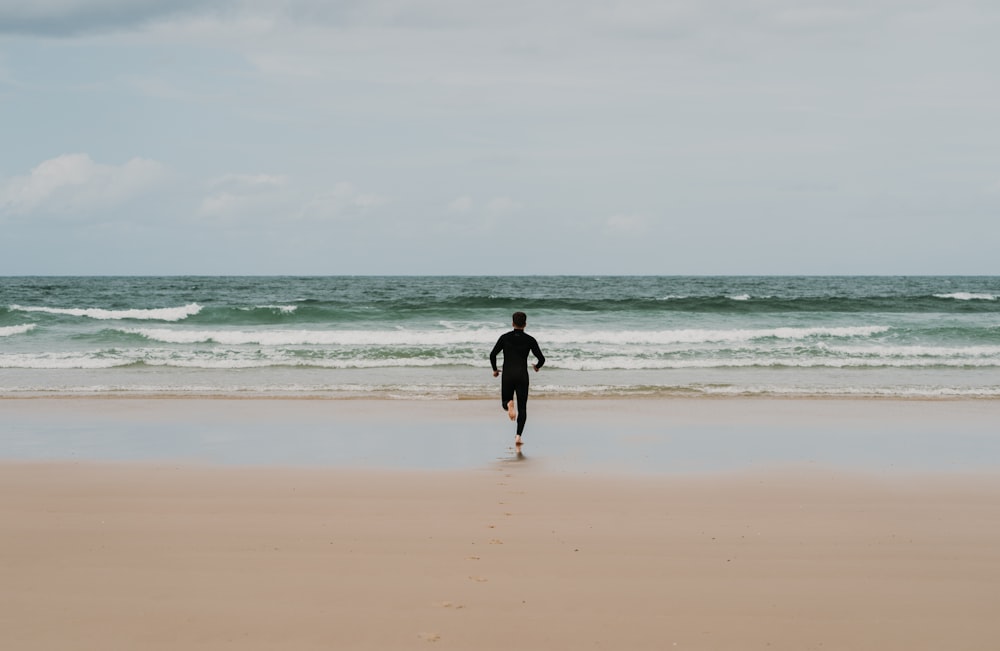 낮 동안 해변을 걷고 있는 검은 셔츠를 입은 남자