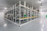 An industrial warehouse aisle lined with rows of polished steel plates glowing under cinematic lighting.