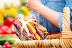A smiling farmer holding a basket of colorful farm-fresh produce with chickens roaming nearby