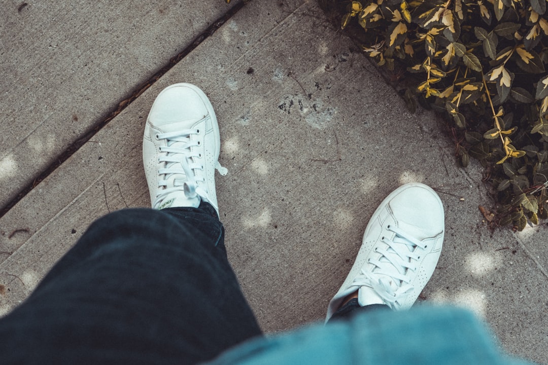 person in blue denim jeans and white sneakers