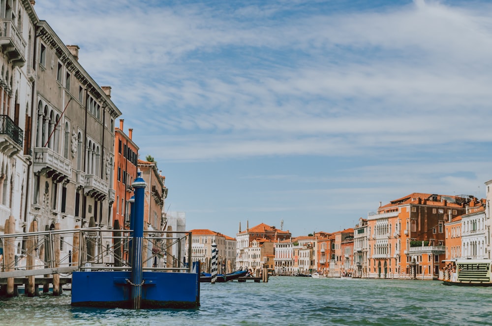 blue boat on water between concrete buildings during daytime