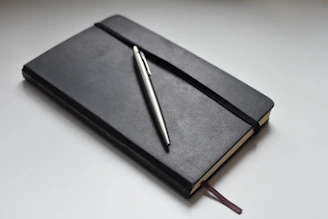 silver click pen on black book