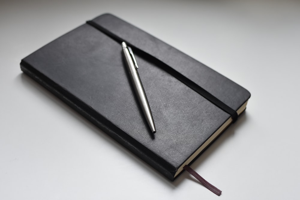 silver click pen on black book