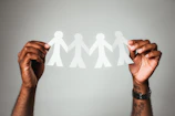 Hands holding layered paper artworks symbolizing migration and identity, captured close up.