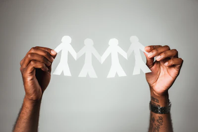Hands holding layered paper artworks symbolizing migration and identity, captured close up.