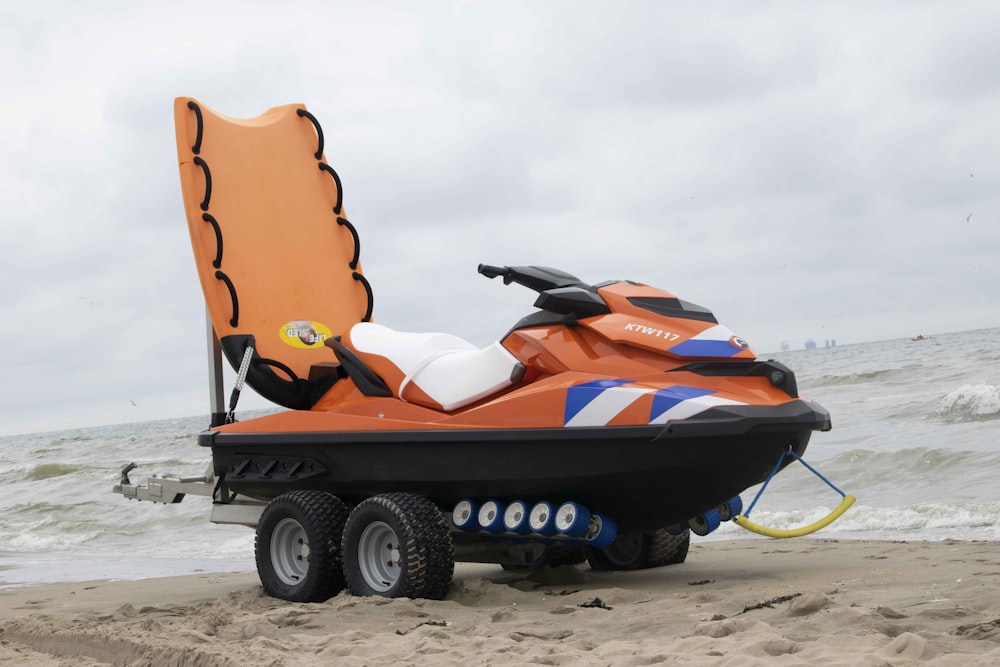blue and orange personal watercraft on beach during daytime