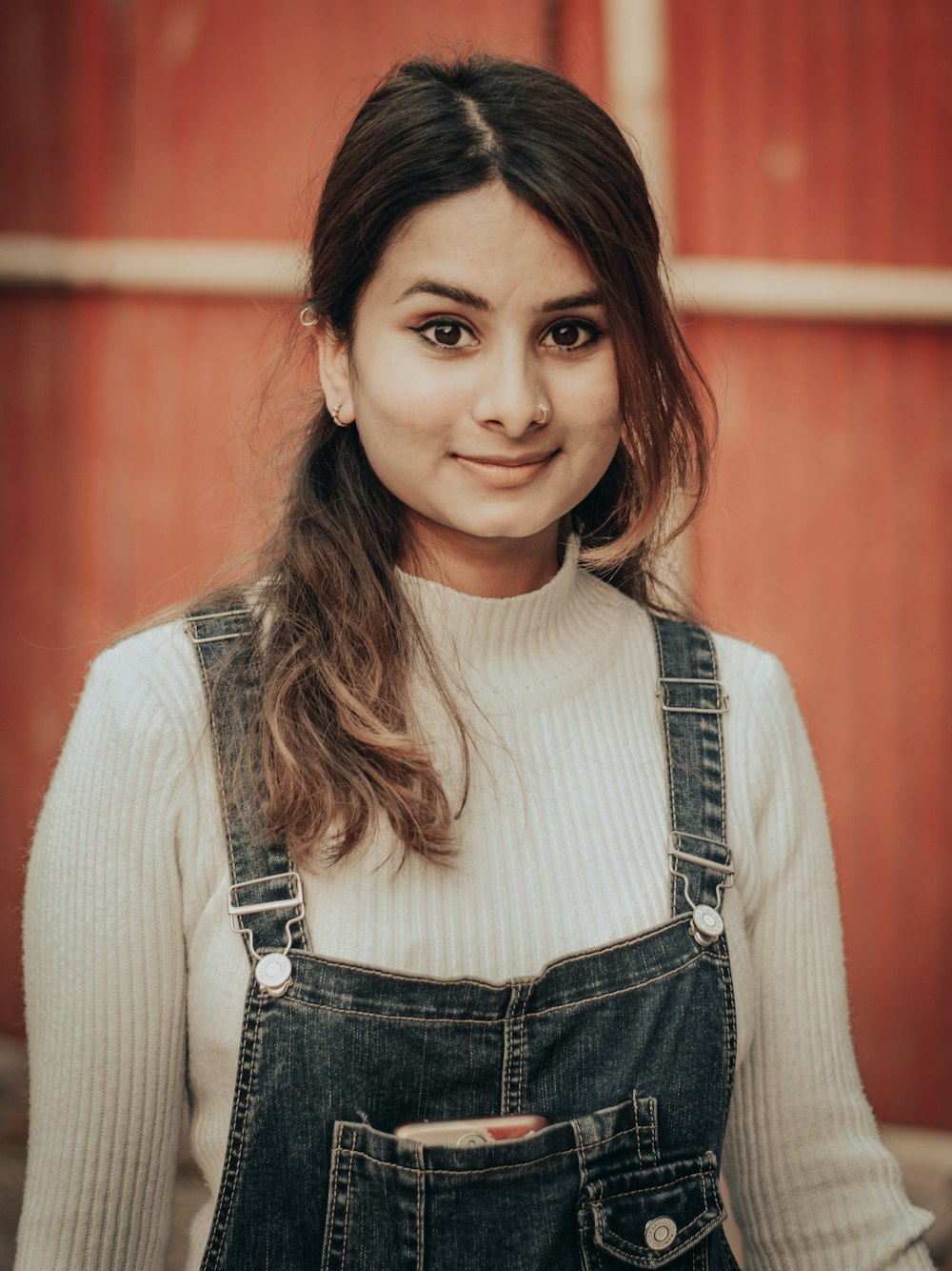 mulher na camisa branca da manga comprida e dungaree jeans azul